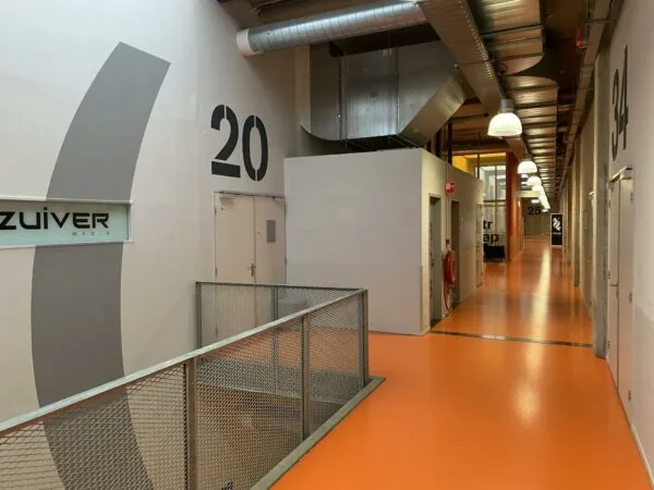 Gang in een modern bedrijfsverzamelgebouw aan de Lulofsstraat met oranje vloer en zicht op meerdere kantoorruimtes, waaronder Zuiver Media.