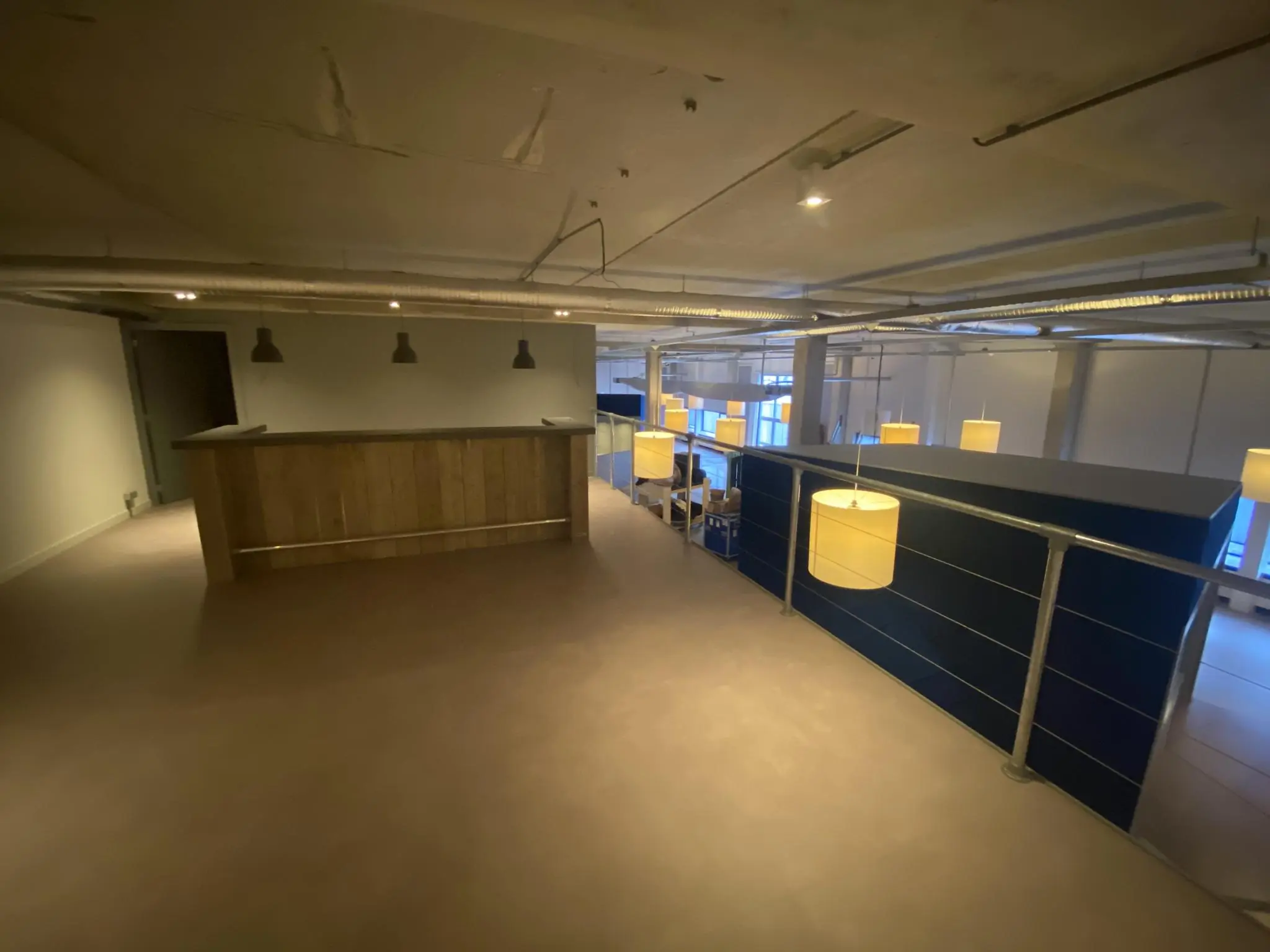 Bovenvloer van een modern kantoorpand aan de Lulofsstraat met een houten bar en hanglampen.
