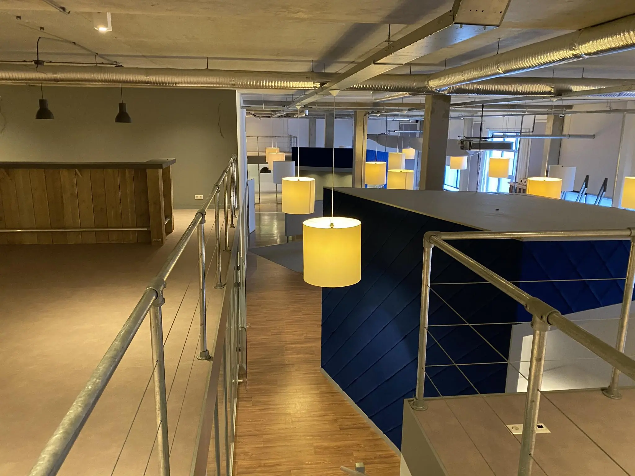 Moderne kantoorruimte aan de Lulofsstraat met industriële afwerking, houten bar en hanglampen.