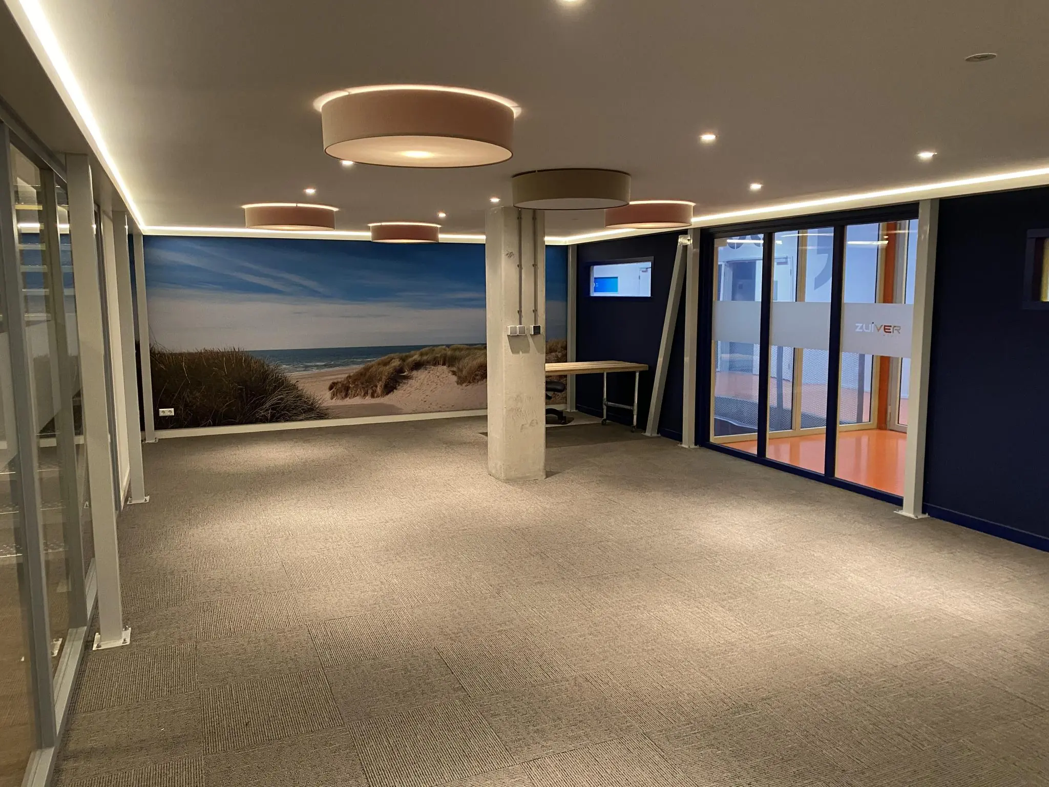Modern kantoorinterieur aan de Lulofsstraat met strandfotobehang en glazen deuren met het logo van Zuiver.