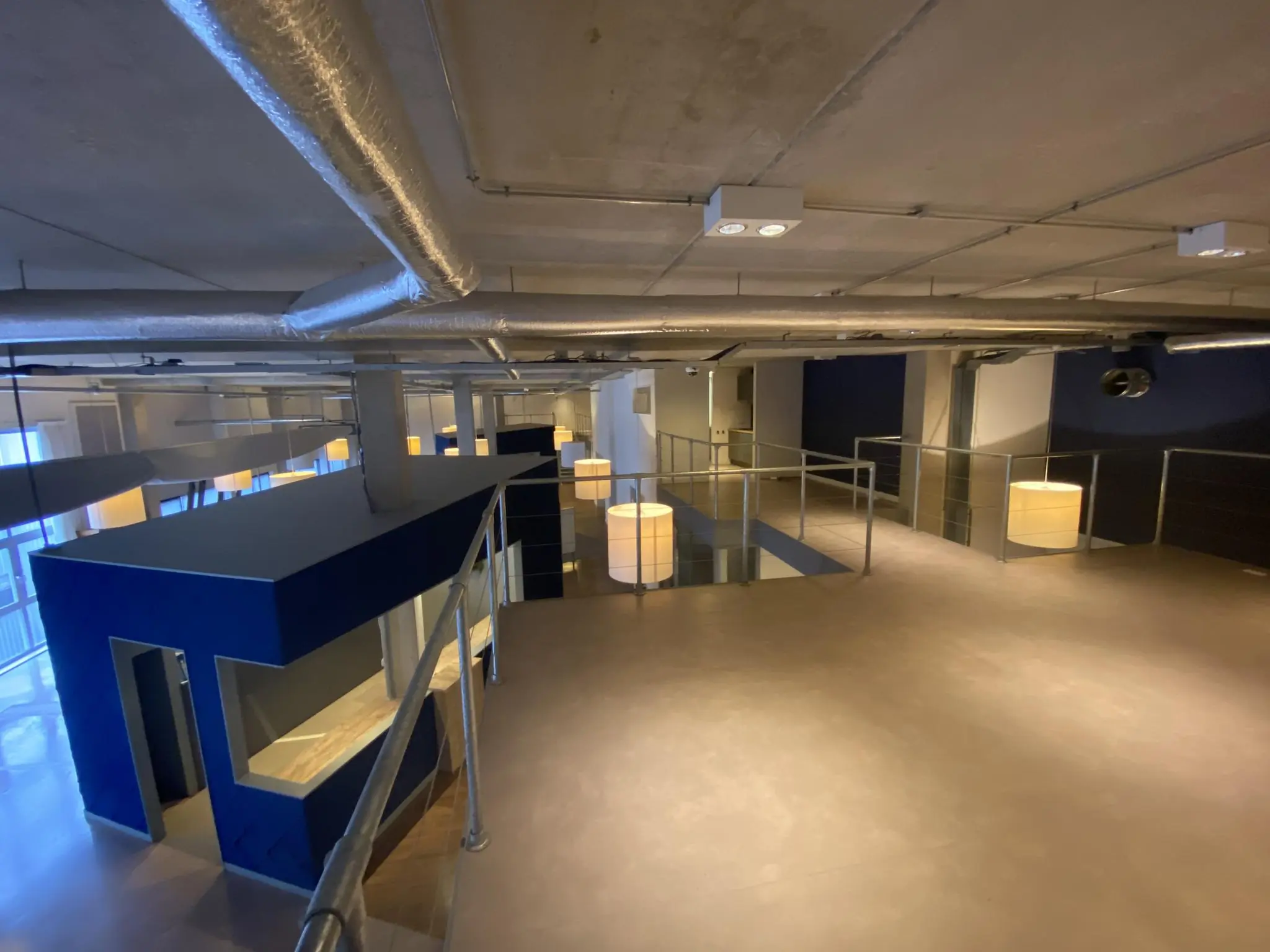 Industriële kantoorruimte aan de Lulofsstraat met betonnen plafond, zichtbare ventilatiebuizen en moderne inrichting.