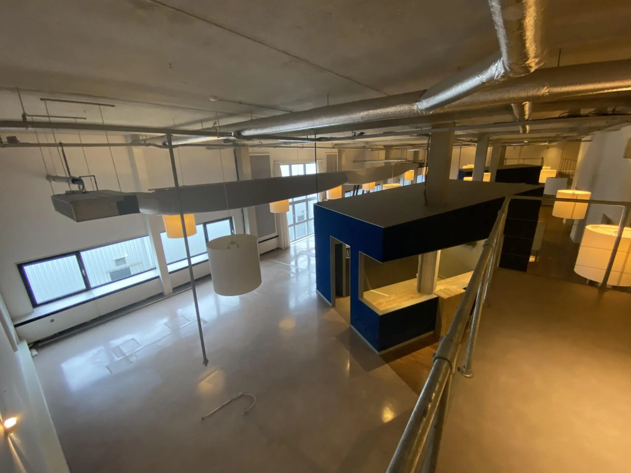Binnenzicht van een industrieel ogende ruimte aan de Lulofsstraat met hoge plafonds, metalen buizen en een blauwe box-in-box constructie.