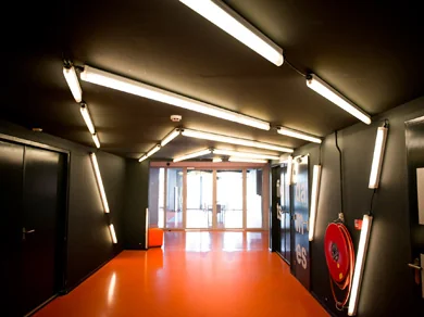 Verlichte gang met oranje vloer en zwarte muren in een gebouw aan de Lulofsstraat.