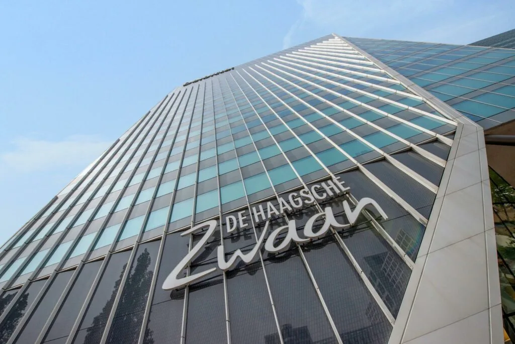 Hoog perspectief van de moderne glazen gevel van kantoorgebouw De Haagsche Zwaan aan de Schenkkade in Den Haag.