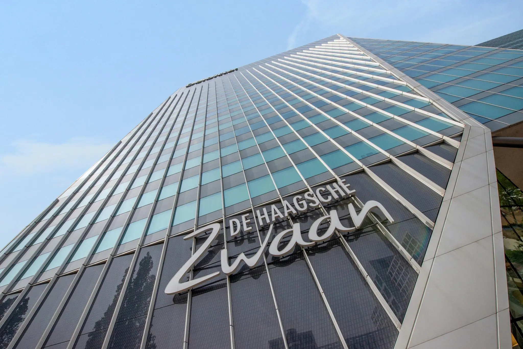 Hoog perspectief van de moderne glazen gevel van kantoorgebouw De Haagsche Zwaan aan de Schenkkade in Den Haag.
