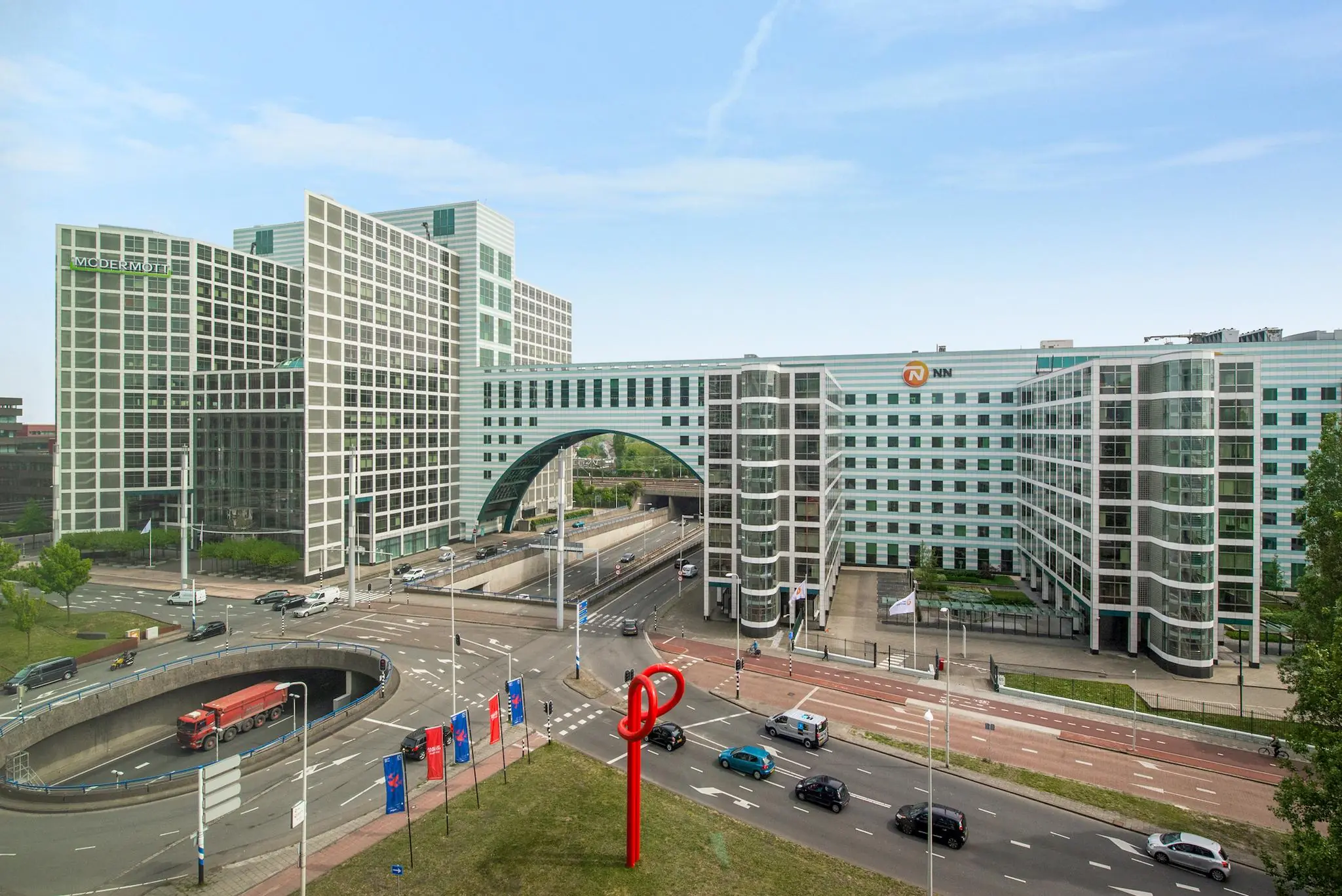 Modern kantoorgebouw aan de Schenkkade in Den Haag met de logo’s van McDermott en NN en een opvallende rode sculptuur op de voorgrond.