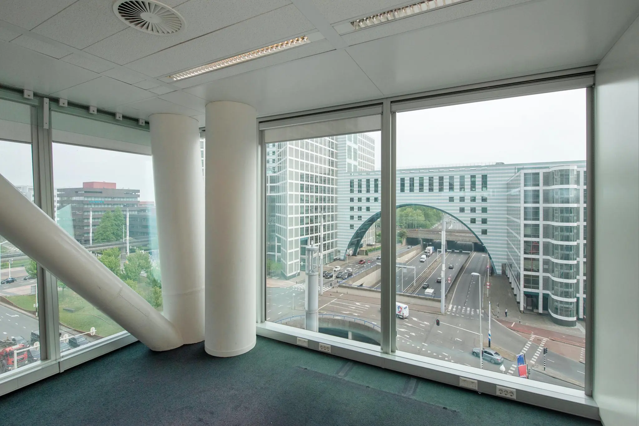 Uitzicht vanuit een modern kantoorpand aan de Schenkkade op een drukke stadsweg en omliggende kantoorgebouwen in Den Haag.