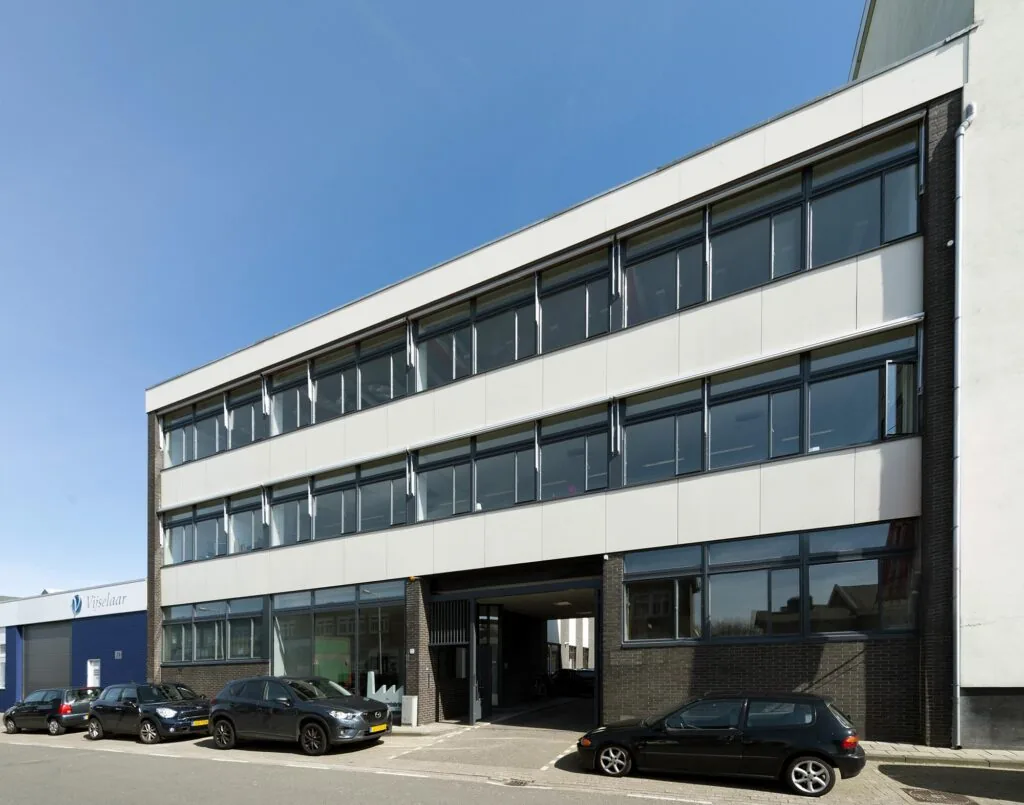 Modern kantoorgebouw aan de Helicopterstraat met grote ramen en geparkeerde auto's ervoor.