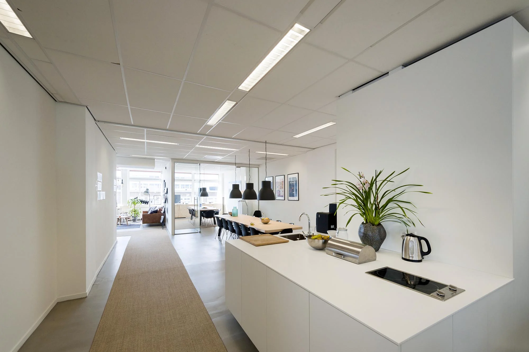 Moderne, open kantoorruimte aan de Helicopterstraat met keuken, vergadertafel en zithoek.