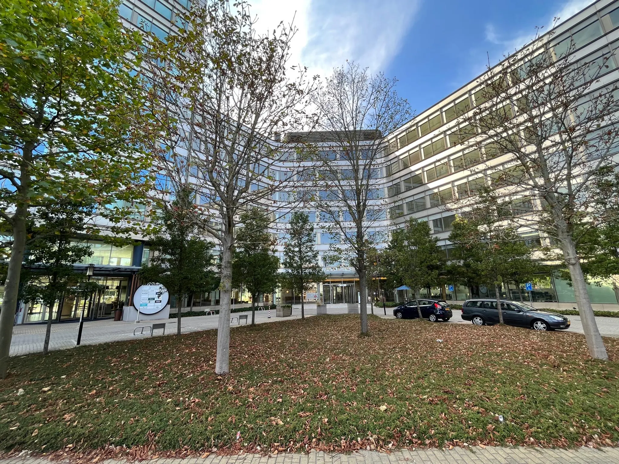 Kantoorgebouw aan de Europalaan met parkeergelegenheid en bomen in herfstkleuren op de voorgrond.