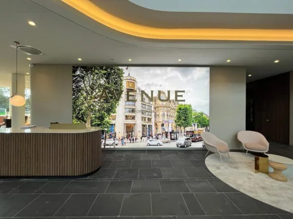 Moderne lobby met een balie, zithoek en groot wandpaneel met afbeelding van de Avenue des Champs-Élysées in Parijs.