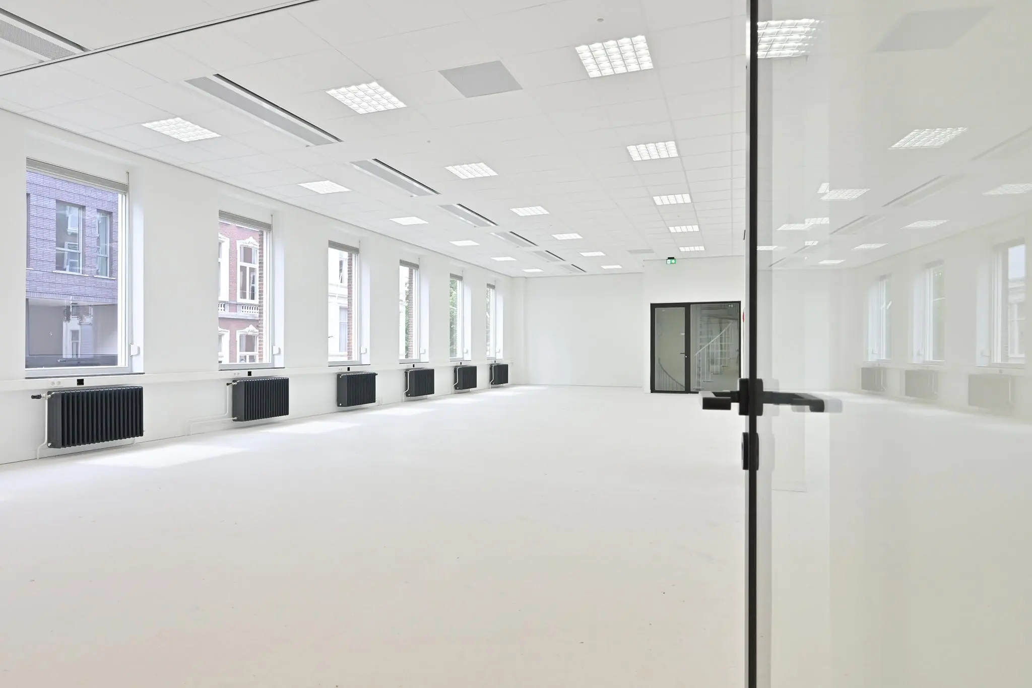 Lichte, lege kantoorruimte aan de Parkstraat met grote ramen en een glazen deur.