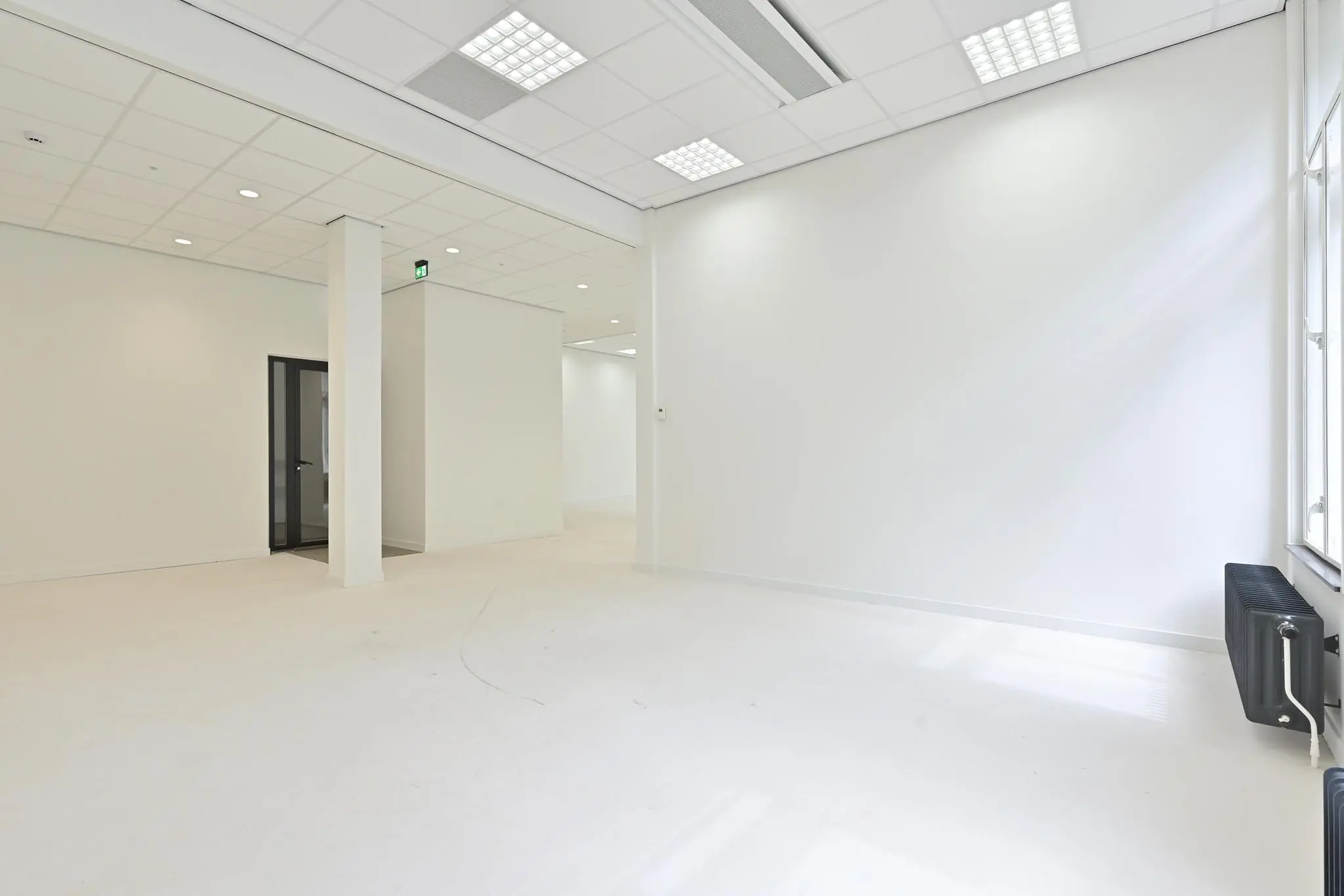 Licht en modern leeg kantoorpand aan de Parkstraat met witte muren, systeemplafond en glazen binnendeur.