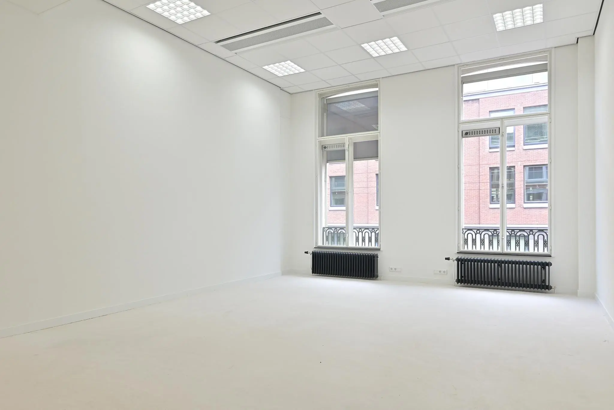 Lichte, lege kantoorruimte aan de Parkstraat met hoge ramen en witte muren.