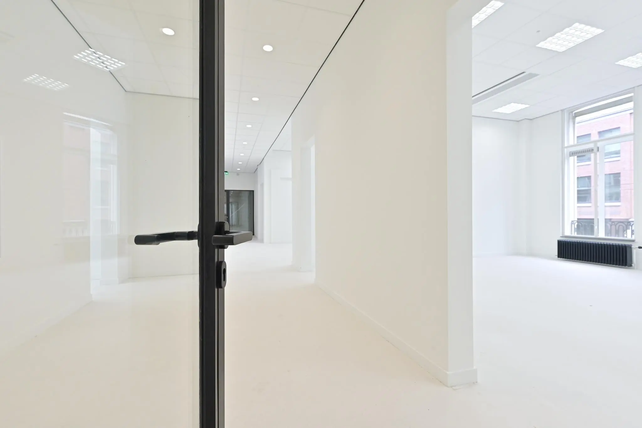 Lichte, lege kantoorruimte aan de Parkstraat met glazen deur en grote ramen.
