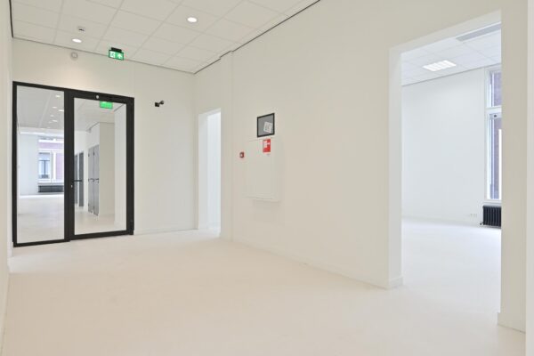 Lichte, moderne hal van een kantoorpand aan de Parkstraat met glazen deuren en zicht op meerdere kamers.
