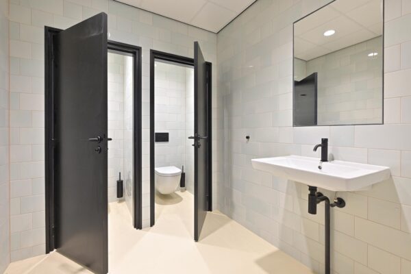 Moderne sanitaire ruimte met twee toiletten en een wastafel aan de Parkstraat.