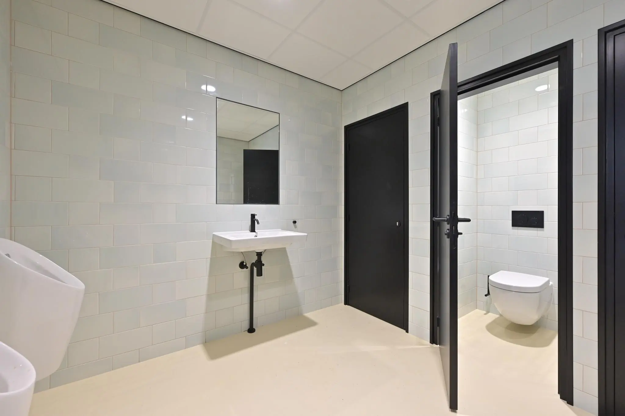 Moderne, betegelde sanitaire ruimte aan de Parkstraat met een wit toilet, zwarte deuren en een wastafel met spiegel.