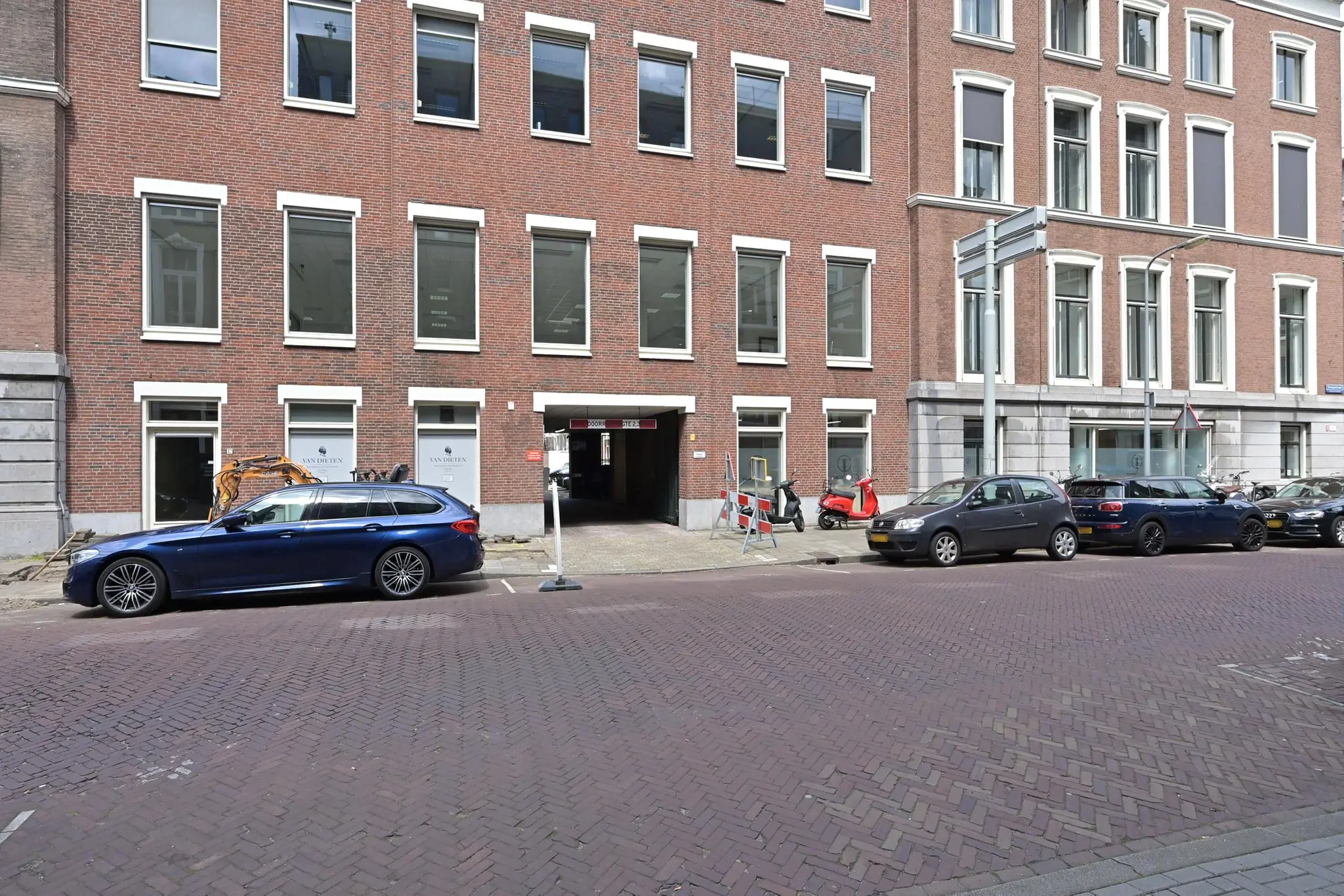 Gevel van een kantoorpand aan de Parkstraat met geparkeerde auto's en een ingang naar een parkeergarage.