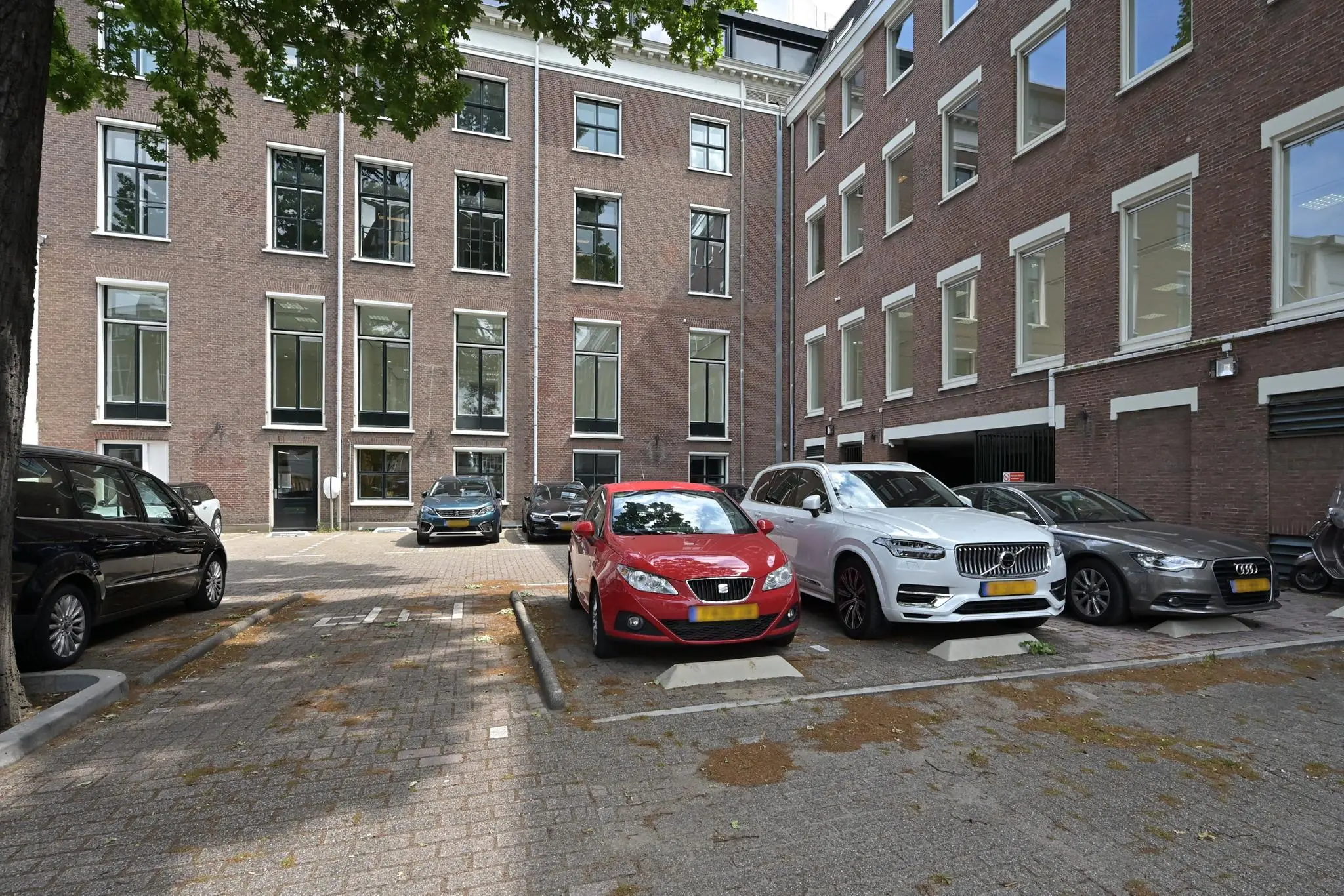 Parkeerplaats aan de Parkstraat met geparkeerde auto's voor een klassiek kantoorgebouw.