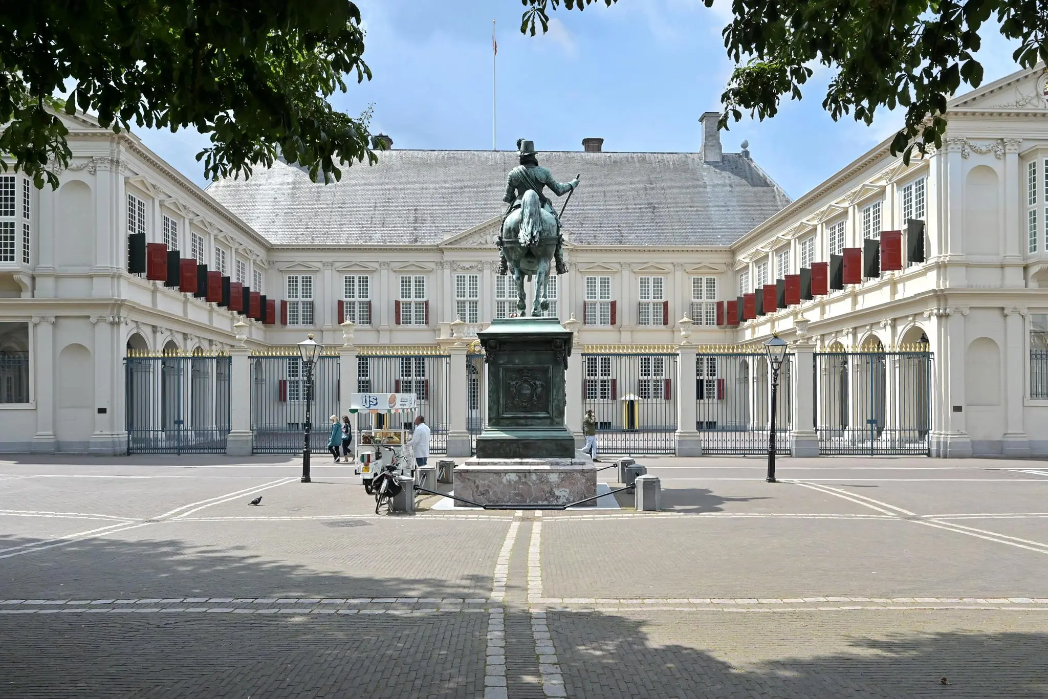 Standbeeld van een ruiter op het voorplein van Paleis Noordeinde in Den Haag met een ijsverkoper op de achtergrond.