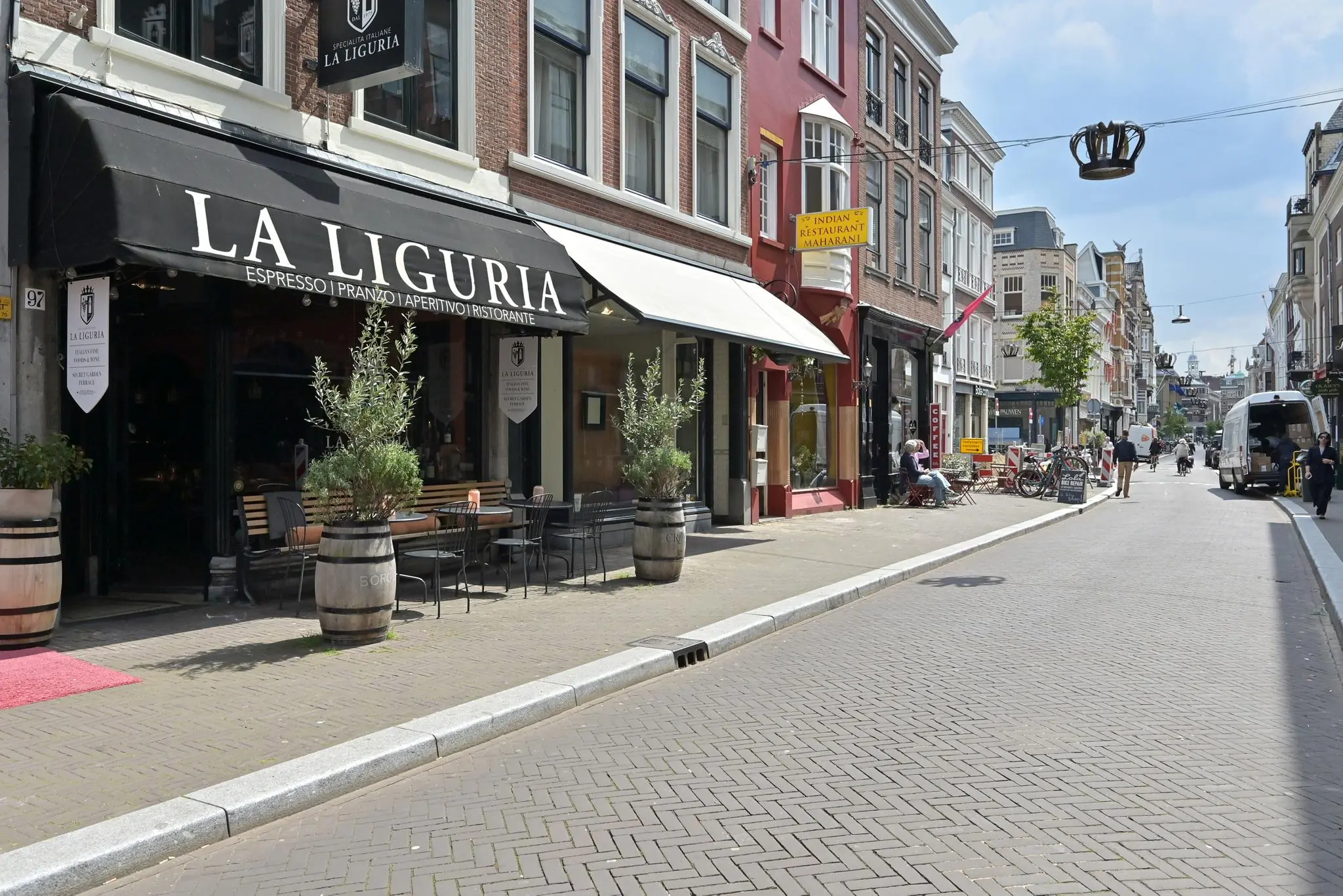 Gezellige straat in Den Haag met restaurants La Liguria en Maharani aan de Parkstraat op een zonnige dag.