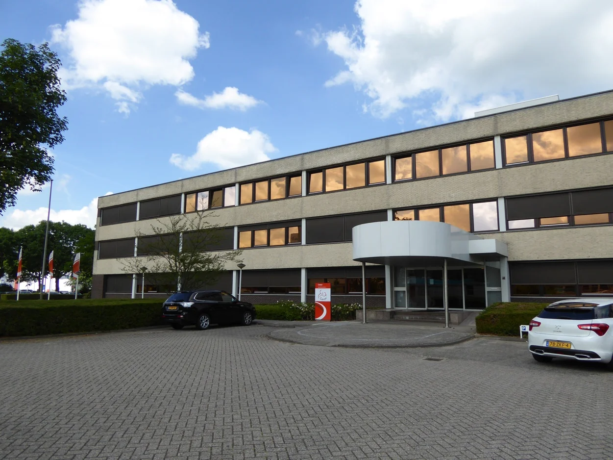 Kantoorgebouw aan de Maarssenbroeksedijk met parkeerplaatsen en auto's op de voorgrond.