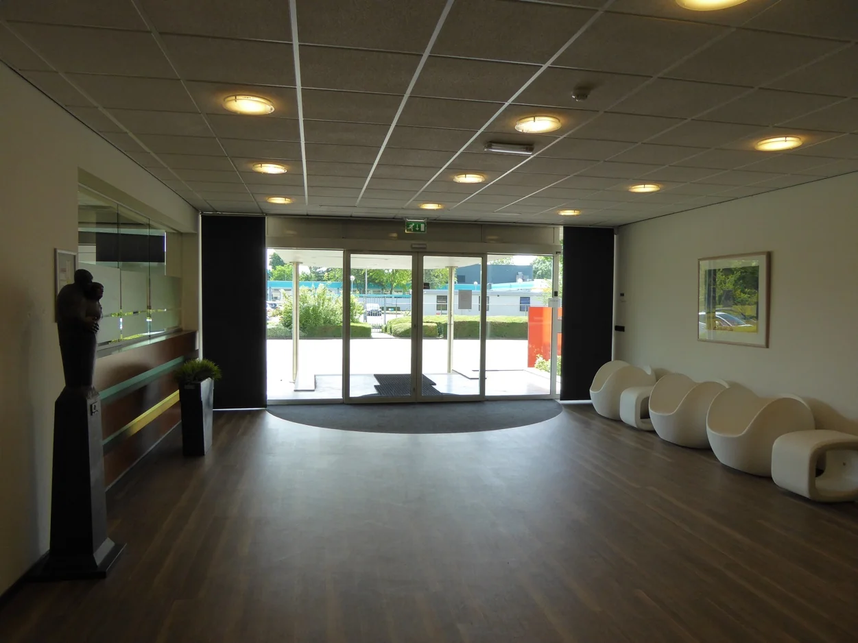 Ingangshal aan de Maarssenbroeksedijk met moderne witte stoelen en glazen schuifdeuren naar buiten.