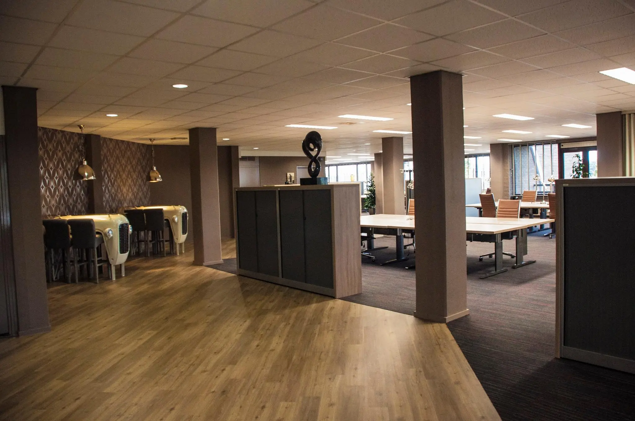 Modern kantoorpand aan de Zaagmolenlaan met open werkplekken, vergadertafels en opvallende bureaus met autogrillelementen.