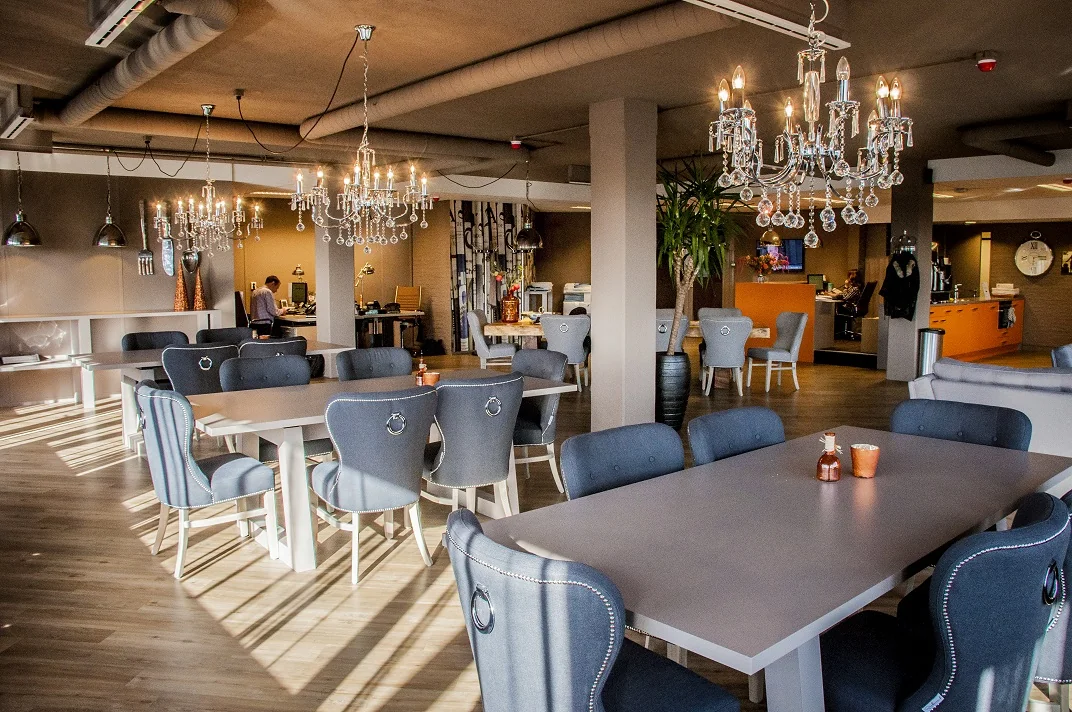 Modern ingericht restaurant aan de Zaagmolenlaan met stijlvolle kroonluchters, grijze stoelen en warme verlichting.