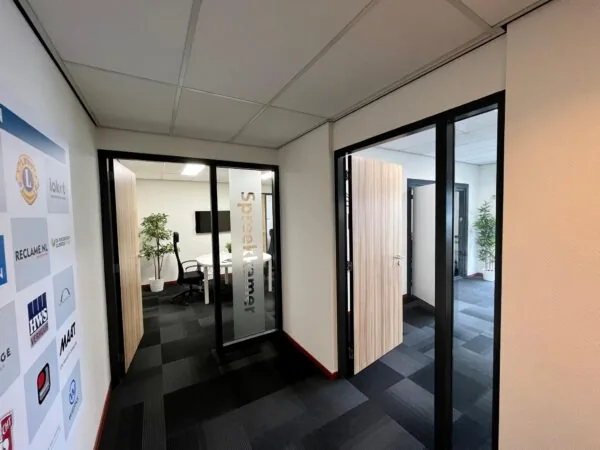 Hal met glazen deuren naar spreekkamers in een modern kantoor aan de Daltonstraat.