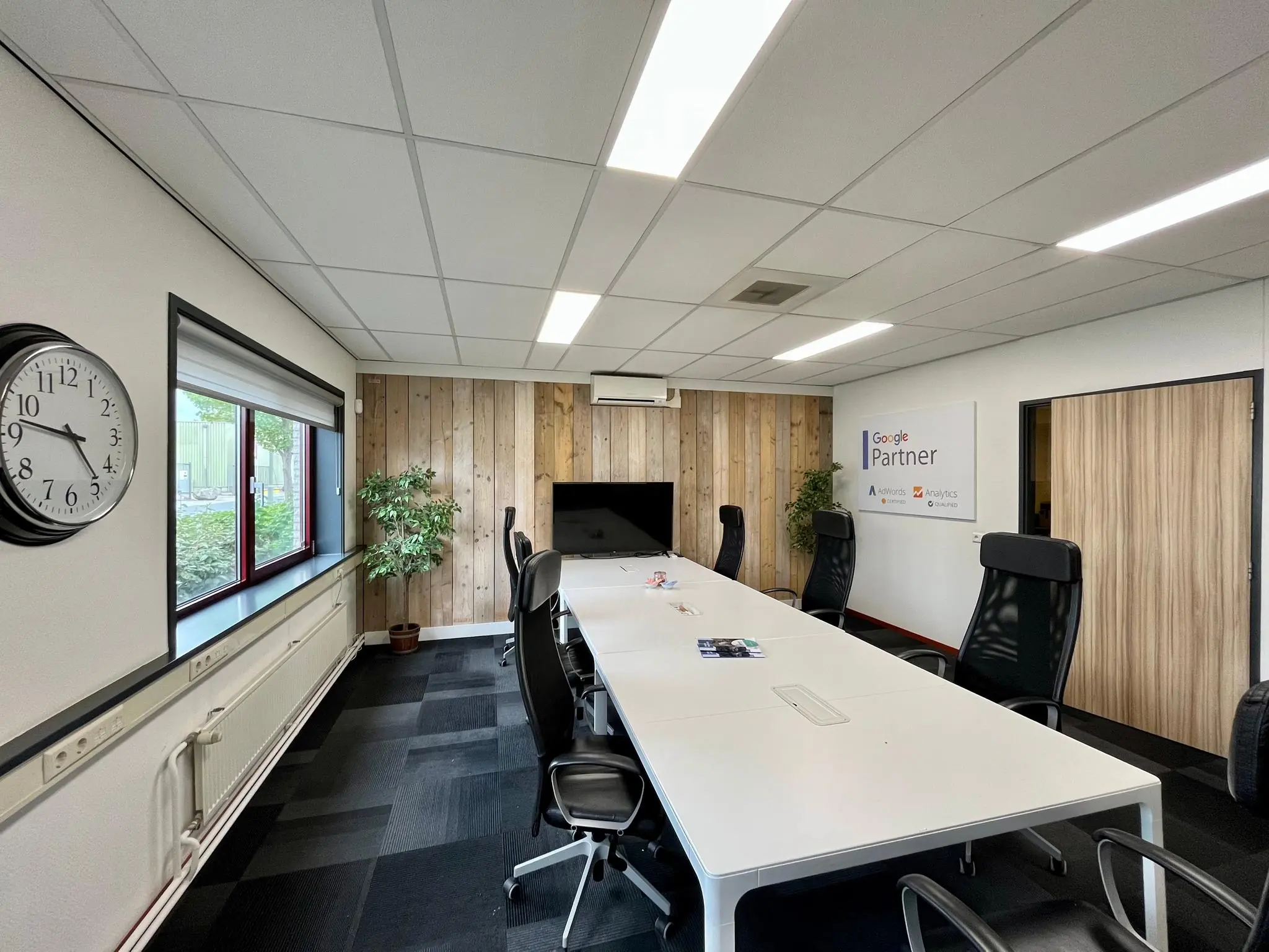 Moderne vergaderruimte aan de Daltonstraat met lange witte tafel, zwarte stoelen en een Google Partner-bord aan de muur.