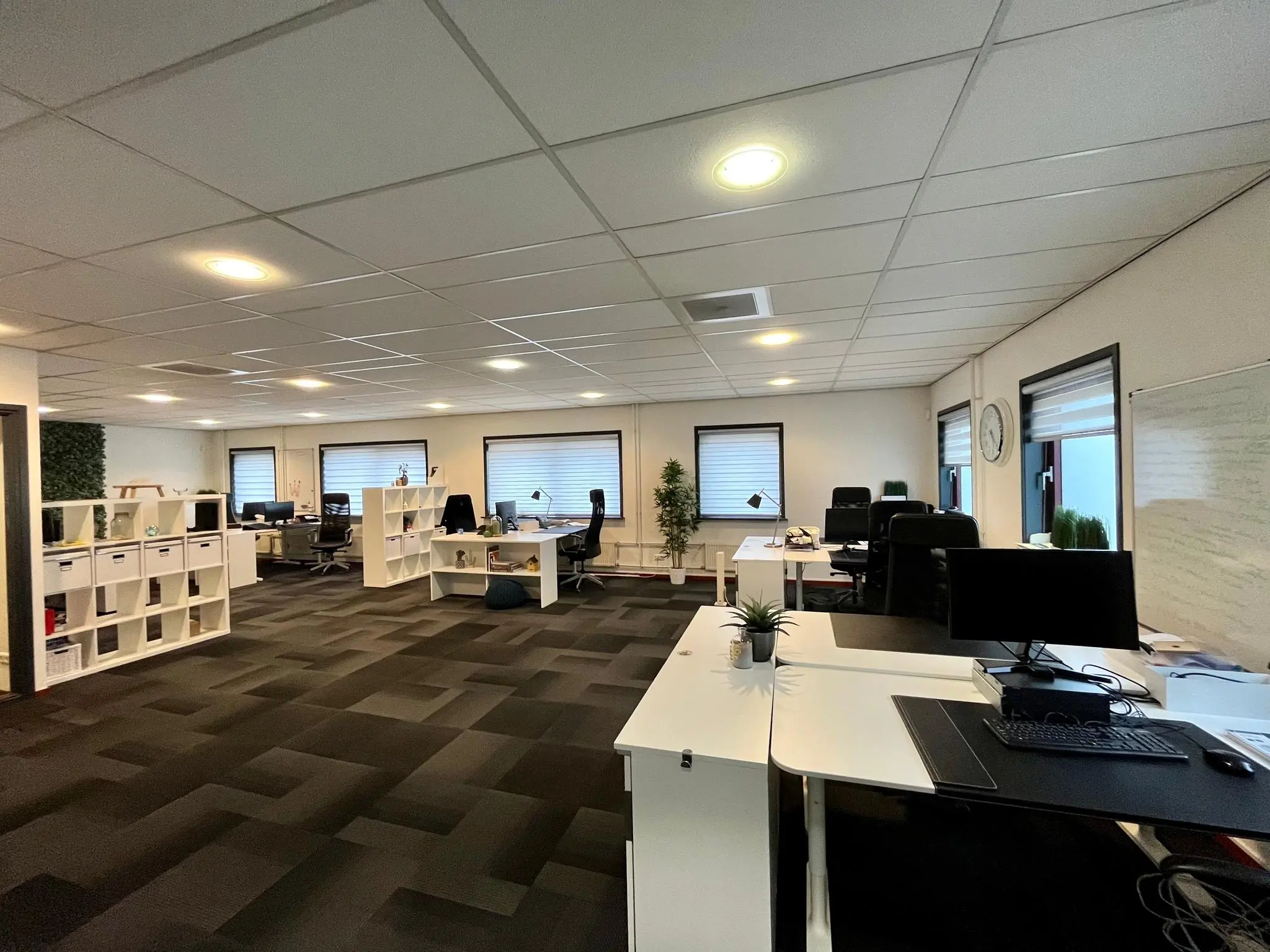Modern ingericht kantoor aan de Daltonstraat met meerdere bureaus, zwarte stoelen en witte kasten in een open werkruimte.