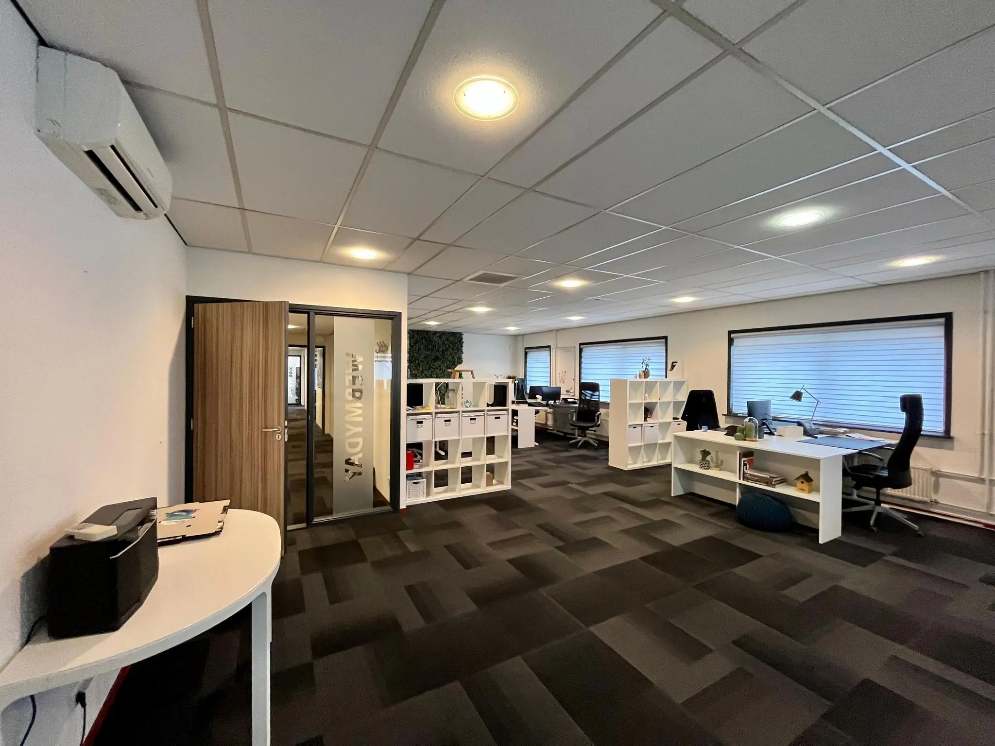 Modern kantoorinterieur aan de Daltonstraat met bureaus, opbergkasten en grote ramen met jaloezieën.