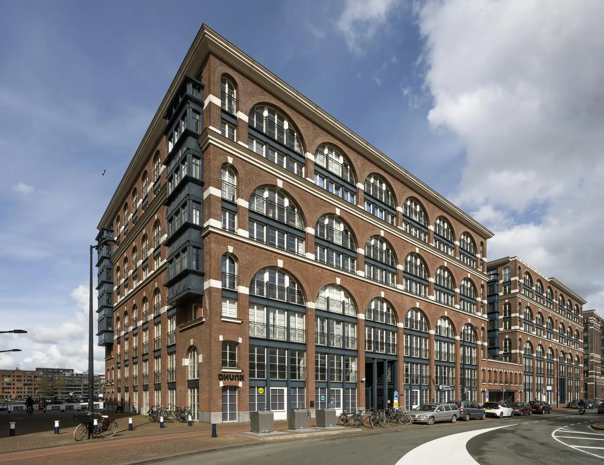 Groot roodbruin bakstenen gebouw met boogvormige ramen aan de Oostelijke Handelskade in Amsterdam.