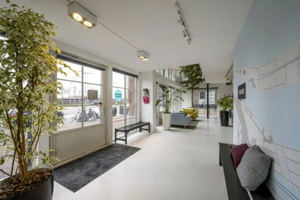 Moderne entreehal aan de Oostelijke Handelskade met veel daglicht, planten en zitgelegenheid.