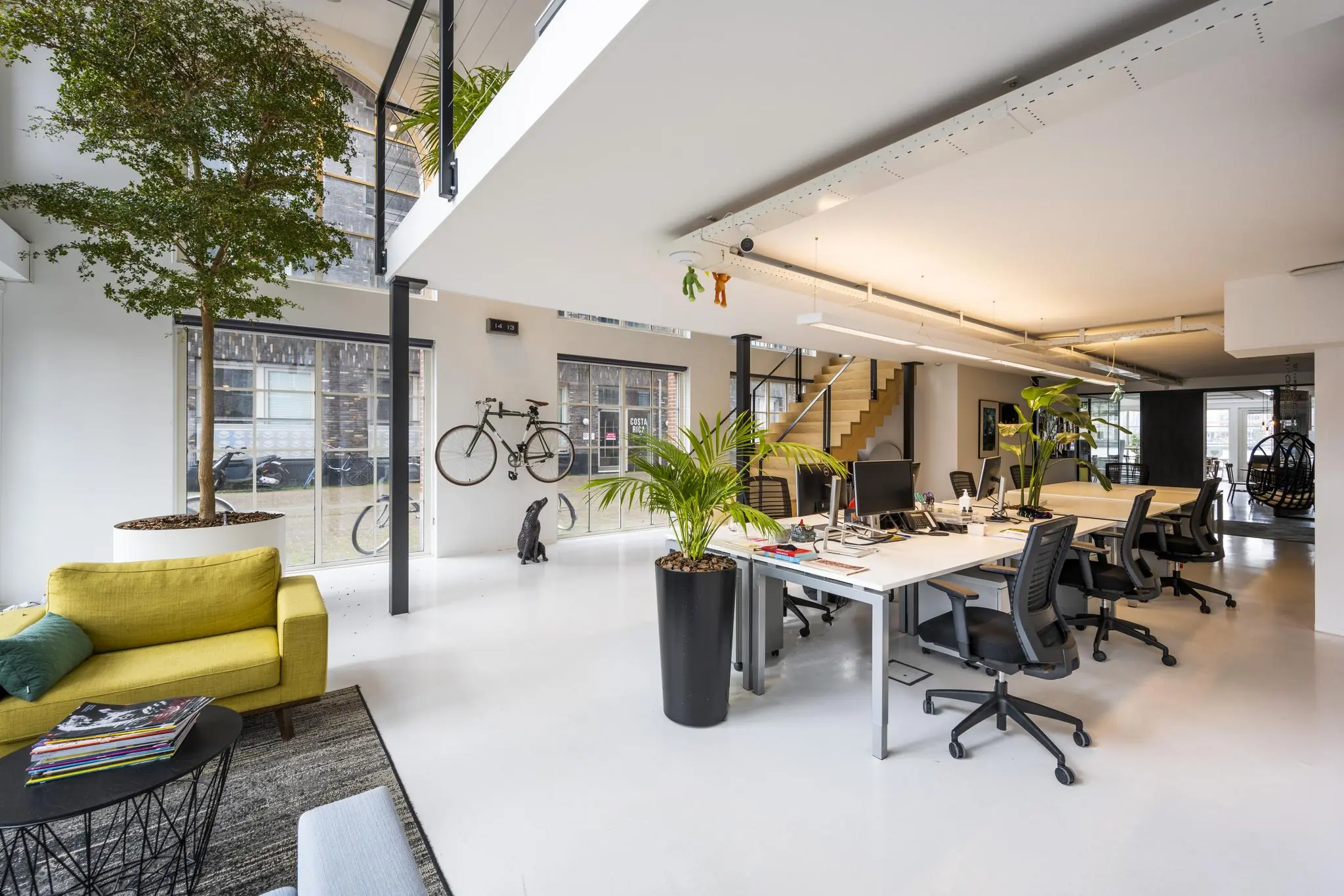 Modern ingericht kantoor aan de Oostelijke Handelskade met open werkplekken, veel planten en natuurlijke lichtinval.