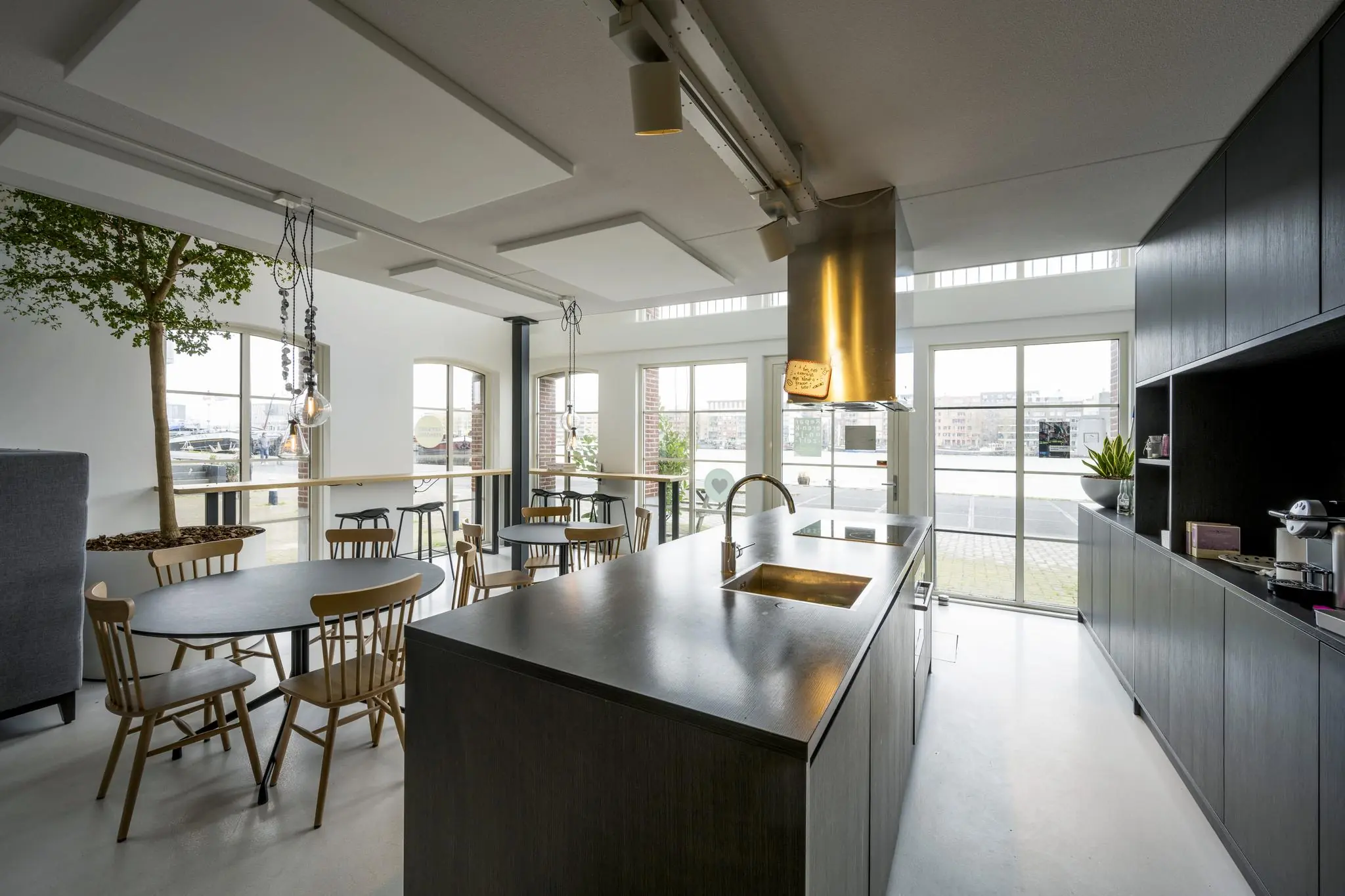 Moderne gezamenlijke keuken met eettafels, kookeiland en uitzicht op het water aan de Oostelijke Handelskade.