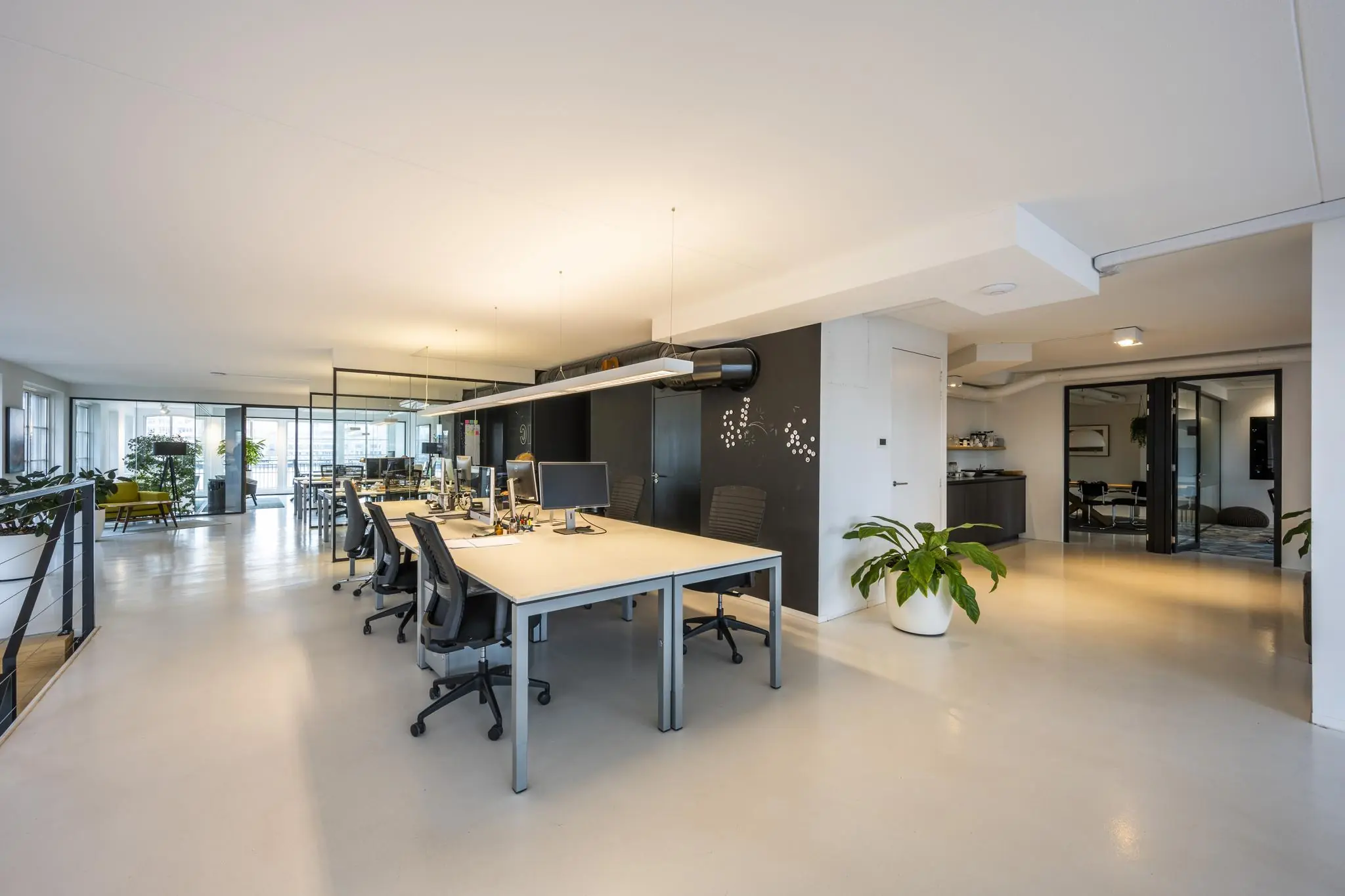 Modern en licht kantoorinterieur aan de Oostelijke Handelskade met open werkplekken, glazen wanden en groene planten.