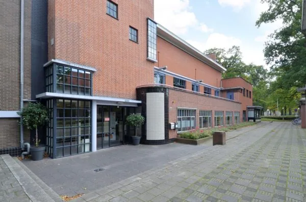 Bakstenen gebouw aan de Endegeesterstraatweg met grote ramen en een bestrate entree.