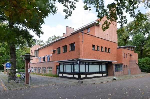 Bakstenen gebouw aan de Endegeesterstraatweg met een opvallende hoekstructuur en omliggende bomen.