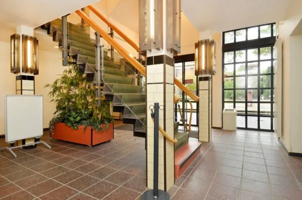 Entreehal van een gebouw aan de Endegeesterstraatweg met groene trap, grote ramen en plantenbak.