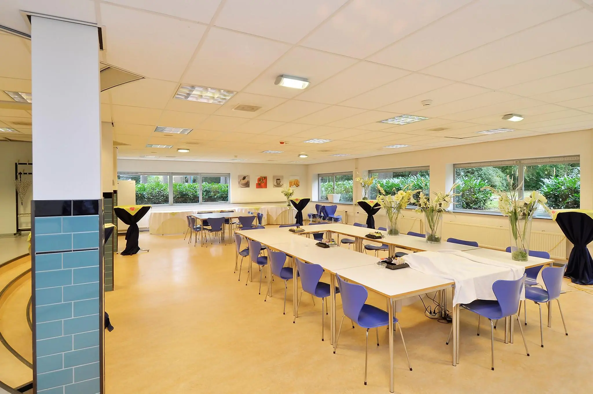 Licht en modern ingerichte vergaderruimte aan de Endegeesterstraatweg met blauwe stoelen, witte tafels en grote ramen met uitzicht op groen.