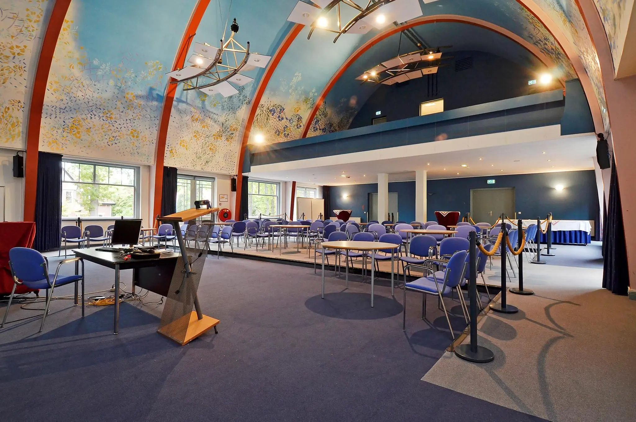 Vergaderruimte met kleurrijk beschilderd gewelf, blauwe stoelen en moderne presentatiefaciliteiten aan de Endegeesterstraatweg.