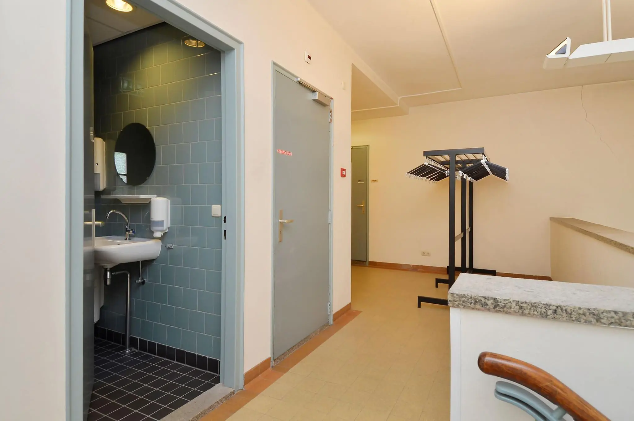 Hal met toegang tot een toiletruimte, een afgesloten deur en een kapstok met plastic kleerhangers aan de Endegeesterstraatweg.