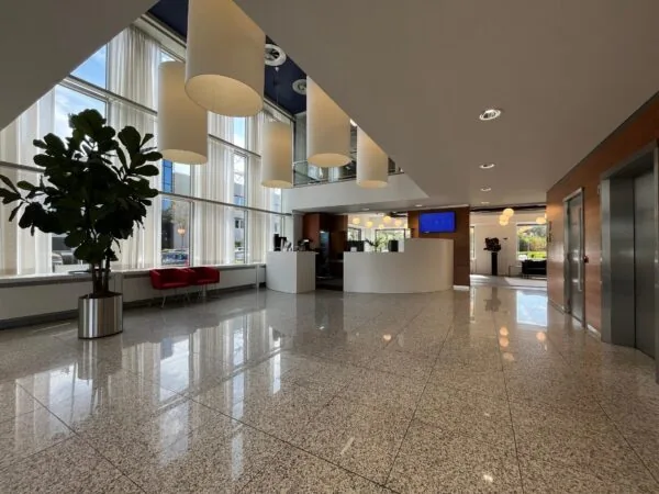 Moderne ontvangsthal aan de Savannahweg met grote ramen, hanglampen, een balie en zithoek.