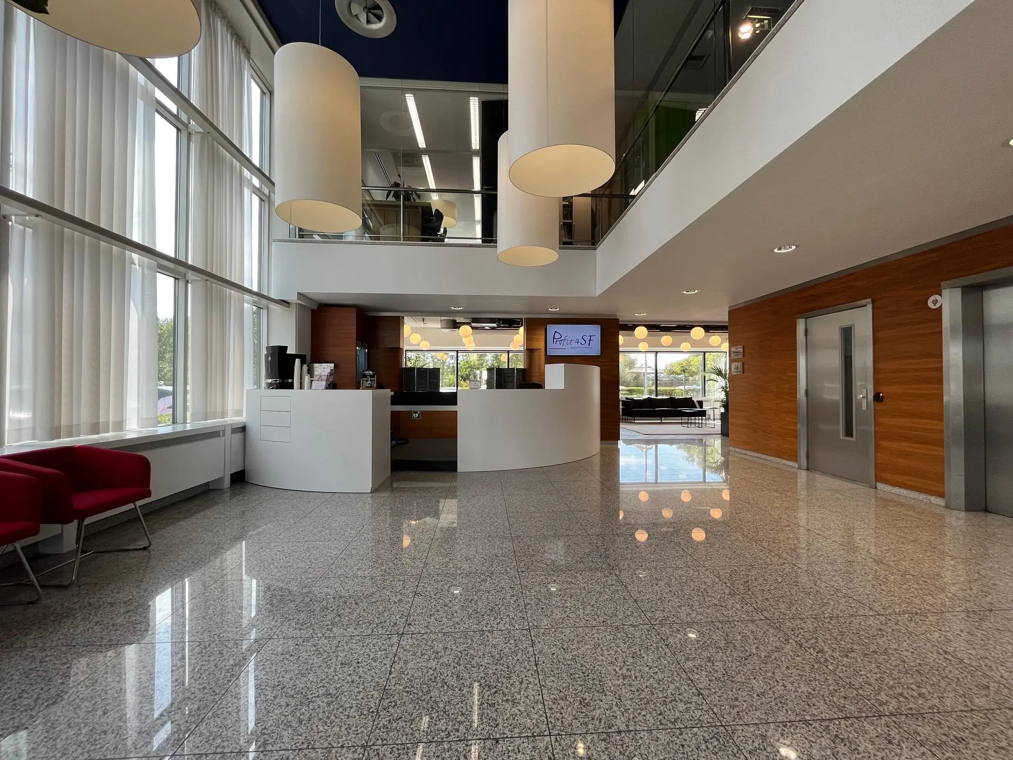 Moderne, lichte ontvangsthal aan de Savannahweg met receptiebalie, zithoeken en een lift.