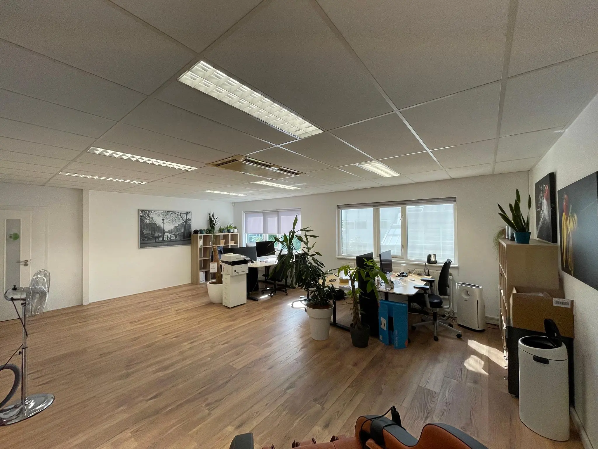 Modern en licht kantoor aan de Computerweg met houten vloer, bureaus, planten en kantoormeubilair.