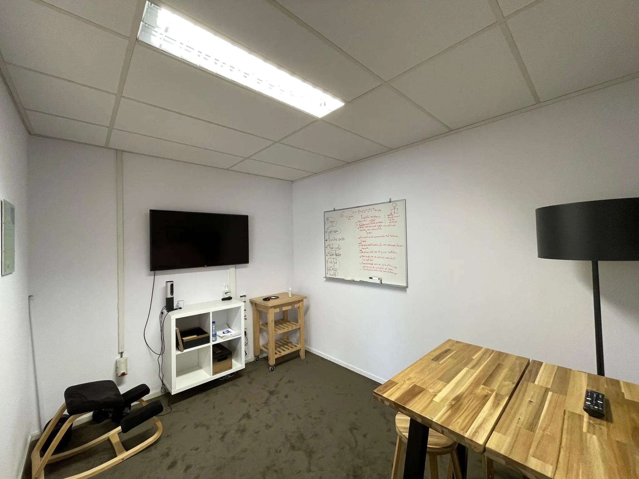 Kleine vergaderruimte aan de Computerweg met een whiteboard, tv-scherm, houten tafel en ergonomische stoel.