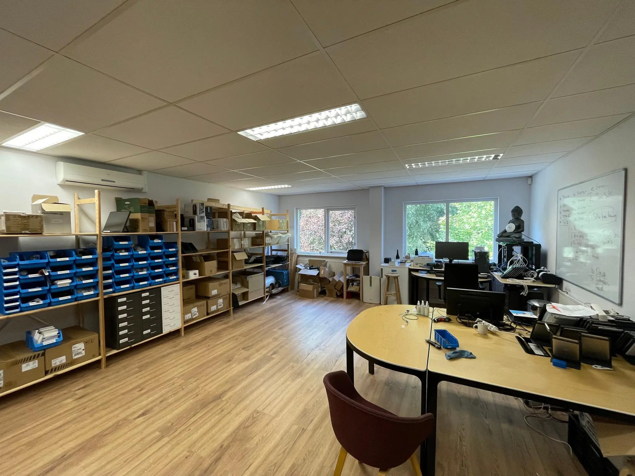 Kantoorruimte aan de Computerweg met bureaus, stellingen vol elektronische apparatuur en een whiteboard aan de muur.